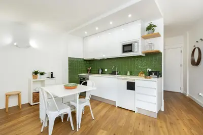 a kitchen with white cabinets and a table and chairs at TENNIS GOLF MAR - Apartamento renovado para 4 com AC e piscina in Vilamoura