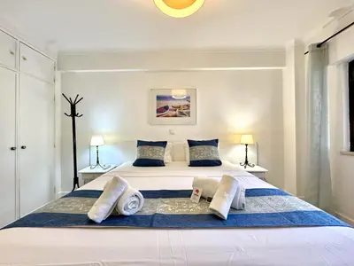 a bedroom with a large white bed with two lamps at Albufeira Cosy by Homing in Albufeira