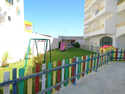 a colorful fence with a playground in front of a building at 1 Bedroom Apartment Chaves, Praceta Vitorino Nemesio, Albufeira in Albufeira