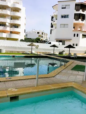 a swimming pool with umbrellas in front of a building at 1 Bedroom Apartment Chaves, Praceta Vitorino Nemesio, Albufeira in Albufeira