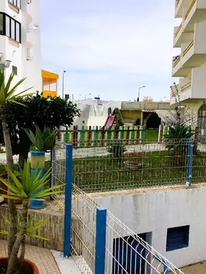a view of a playground with a fence and plants at 1 Bedroom Apartment Chaves, Praceta Vitorino Nemesio, Albufeira in Albufeira
