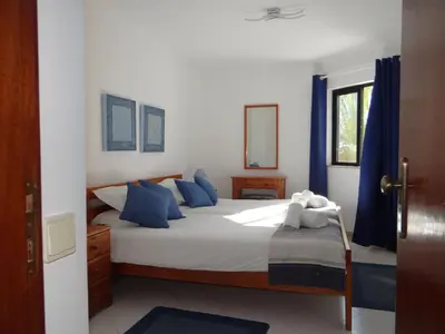 a bedroom with a large bed with blue pillows at Porto Marina @Vilamoura in Vilamoura