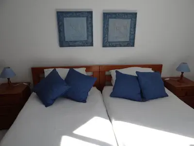 two beds with blue pillows in a bedroom at Porto Marina @Vilamoura in Vilamoura