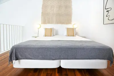 a white bedroom with a bed with a gray blanket at Vacation Time Apartment in Faro