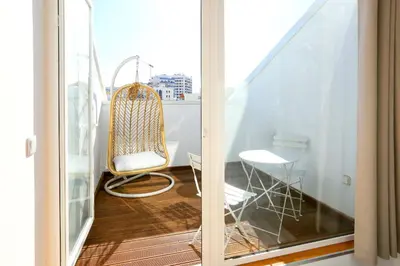 a balcony with a rattan chair and a table at Vacation Time Apartment in Faro