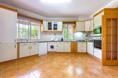 a kitchen with white cabinets and a tile floor at Villa Ocre in Galé