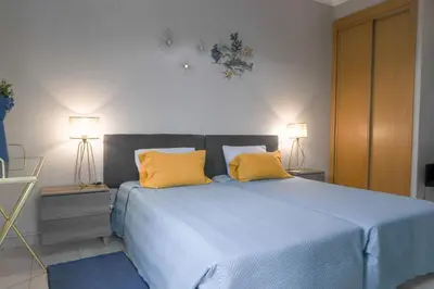 a bedroom with a blue bed with two yellow pillows at Agua Viva by Umbral in Albufeira