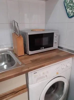 a kitchen with a microwave and a washing machine at Apartamento Batalha - Quarteira, Algarve, Portugal in Quarteira