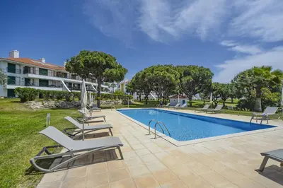 a swimming pool with lounge chairs next to a building at Vila Sol Apartamento fantástico 3 quartos piscina in Quarteira