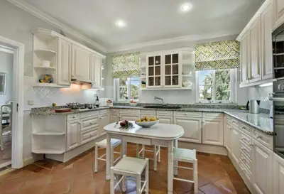 a kitchen with white cabinets and a white table and chairs at Quinta do Lago 2-Bed Apartment - Golf Pool & Ac in Faro