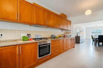 a kitchen with wooden cabinets and a stove top oven at V3 Olhos dÁgua com piscina AC wifi 800m praia in Olhos de Água