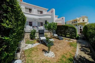 a white house with two chairs in the yard at V3 Olhos dÁgua com piscina AC wifi 800m praia in Olhos de Água