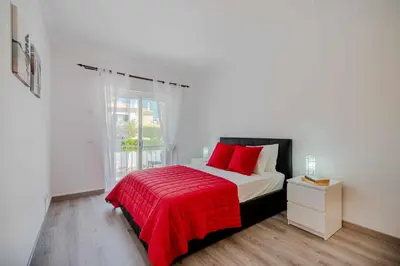 a bedroom with a bed with a red blanket and a window at V3 Olhos dÁgua com piscina AC wifi 800m praia in Olhos de Água