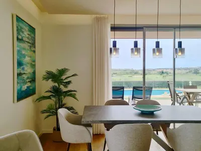 a dining room with a table and chairs and a window at La Vila Nature, Laguna Village 246-Clever Details, Luxury apartment, located in a quiet area, BBQ and free Wi-Fi in Vilamoura