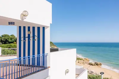 a house with a blue and white door and the beach at Monicca Collection Suites and Residences in Albufeira