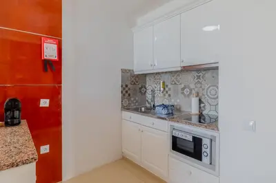 a kitchen with white cabinets and a microwave at Monicca Collection Suites and Residences in Albufeira