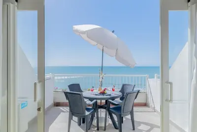 a table with chairs and an umbrella on a balcony at Monicca Collection Suites and Residences in Albufeira