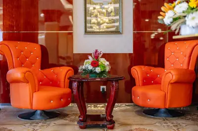 two orange chairs and a table with flowers on it at Monicca Collection Suites and Residences in Albufeira