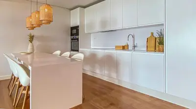 a kitchen with white cabinets and a kitchen island with chairs at YES! Incrível Vista Piscina T2 HsR Vilamarina in Vilamoura