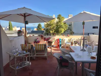 a patio with tables and chairs and an umbrella at Albufeira Home in Albufeira