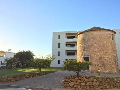 a building with a tower next to a stone wall at Albufeira Home in Albufeira