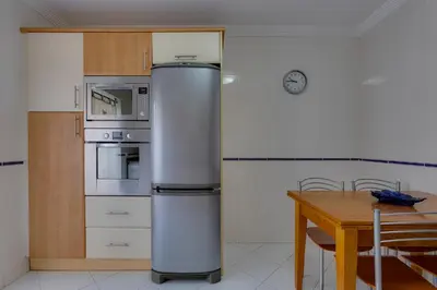 a kitchen with a refrigerator and a wooden table at JAZZ & SILVIA - Moderno & Central apenas a 5 min da praia dos Pescadores in Albufeira
