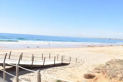 a sandy beach with a wooden pier and the ocean at Cosy flat, Salgados Village in Guia