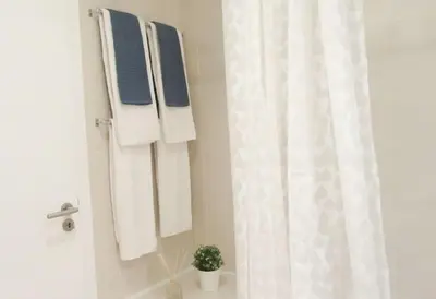 a bathroom with white towels and a shower curtain at Cosy flat, Salgados Village in Guia