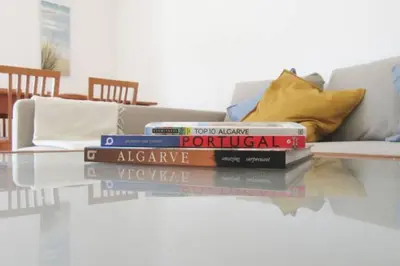 a stack of books on a glass table in front of a couch at Cosy flat, Salgados Village in Guia