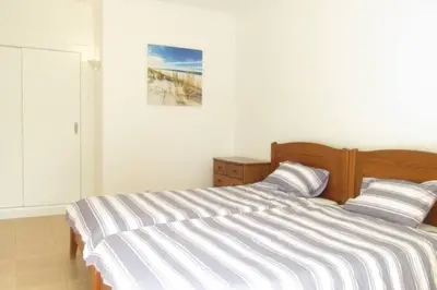a bedroom with a bed with a striped bedspread at Cosy flat, Salgados Village in Guia