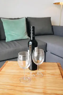 a bottle of wine and two wine glasses on a table at Host Wise - Sweet & Sunny Flat - Ace Location in Quarteira