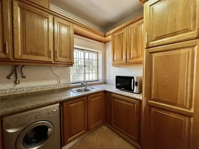 a kitchen with wooden cabinets and a sink and a microwave at Quarteira Classic 1 With Pool by Homing in Quarteira