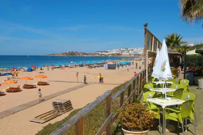 a beach with chairs and umbrellas and people at Quinta da Barracuda Prime Sea View Apartment in Albufeira