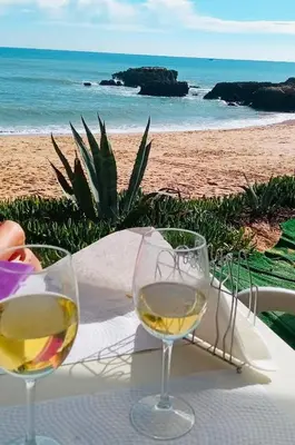 two glasses of wine sitting on a table near the beach at Quinta da Barracuda Prime Sea View Apartment in Albufeira