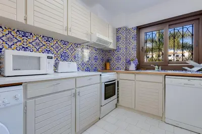 a kitchen with white appliances and blue and white tiles at CASA NINI - Apart para 6 com AC e a 100 m da praia Mónica Isabel in Albufeira