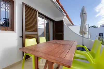 a dining room with a wooden table and green chairs at CASA NINI - Apart para 6 com AC e a 100 m da praia Mónica Isabel in Albufeira