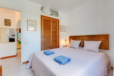 a bedroom with a white bed with two towels on it at CASA NINI - Apart para 6 com AC e a 100 m da praia Mónica Isabel in Albufeira