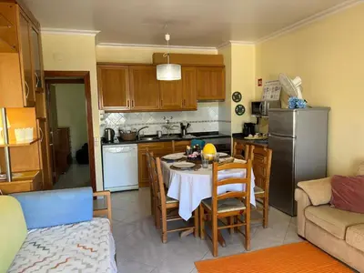 a kitchen with a table with chairs and a refrigerator at Infante Sagres by FHR1º linha da praia in Quarteira
