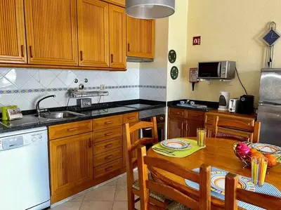 a kitchen with wooden cabinets and a wooden table with a tableablish at Infante Sagres by FHR1º linha da praia in Quarteira