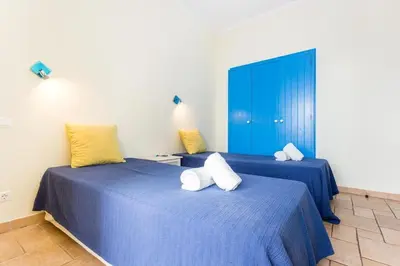 two beds in a room with blue and yellow pillows at Refurbished beachfront house, Pool, AC, WiFi, Albufeira, sea view in Albufeira