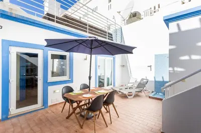 a dining room with a table and an umbrella at Refurbished beachfront house, Pool, AC, WiFi, Albufeira, sea view in Albufeira