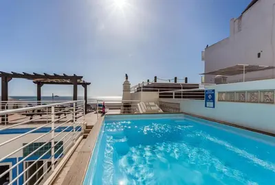 a swimming pool on top of a building with the ocean in the background at Refurbished beachfront house, Pool, AC, WiFi, Albufeira, sea view in Albufeira