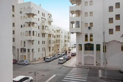 a street with cars parked in front of tall buildings at Apartamento Peron in Quarteira