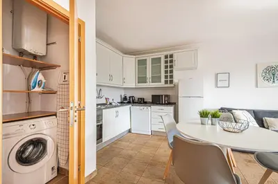 a kitchen and dining room with a white table and chairs at BeGuest Copacabana Vilamoura Apartment in Quarteira