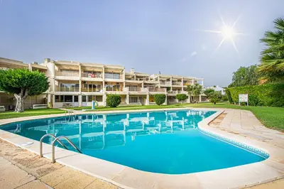 a swimming pool with chairs in front of a building at BeGuest Copacabana Vilamoura Apartment in Quarteira