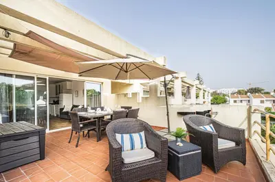 a patio with a table and chairs and an umbrella at BeGuest Copacabana Vilamoura Apartment in Quarteira