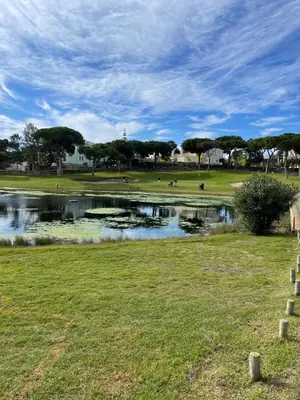 a pond in a park with people playing golf at House of Rising Sun in Quarteira