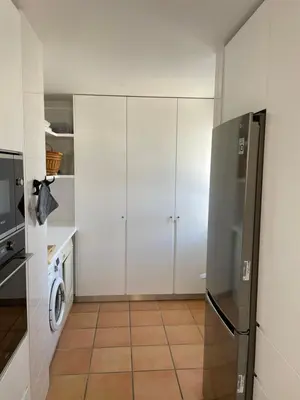 a kitchen with white cabinets and a stainless steel refrigerator at House of Rising Sun in Quarteira
