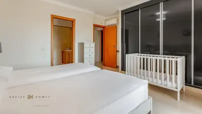 a bedroom with a large white bed and a crib at Luxuosa moradia V5 em Quarteira - Greice Homes in Quarteira