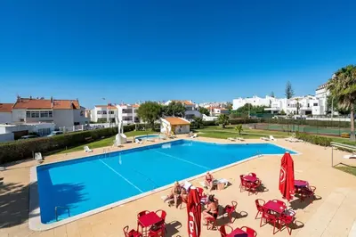 a large swimming pool with tables and chairs at SILCHORO - Estúdio remodelado com AC e piscina in Albufeira
